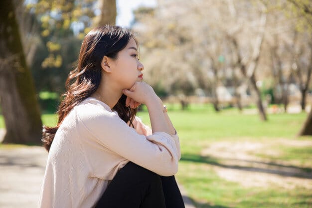 asian girl feeling sad by the park